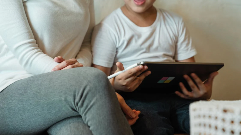 the child is reading something on the tablet together with his mother