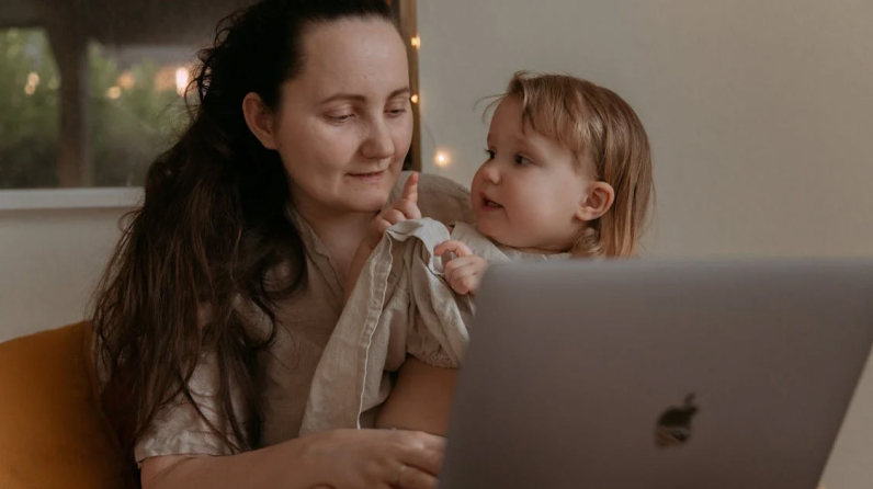 mother and child are looking at a laptop on the sofa